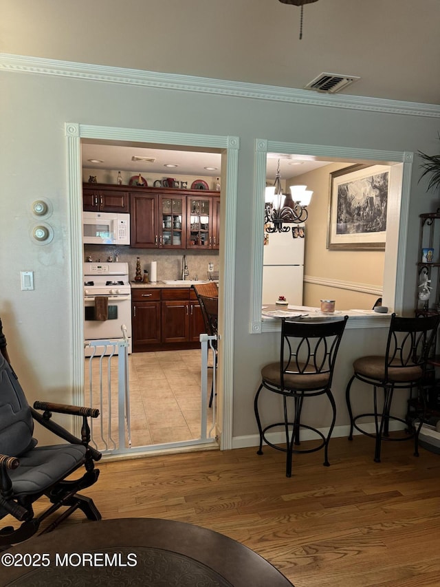 16B Robin St Unit 16B, Manchester, NJ 08759 - bar area with white appliances, light wood-type flooring, a sink, ornamental molding, and a chandelier