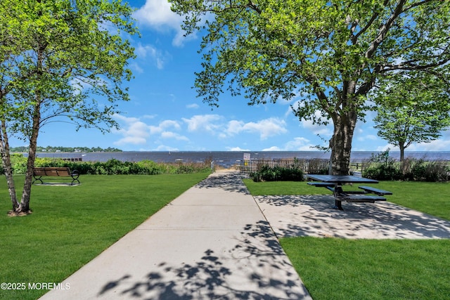 view of community with a lawn, a water view, and a patio