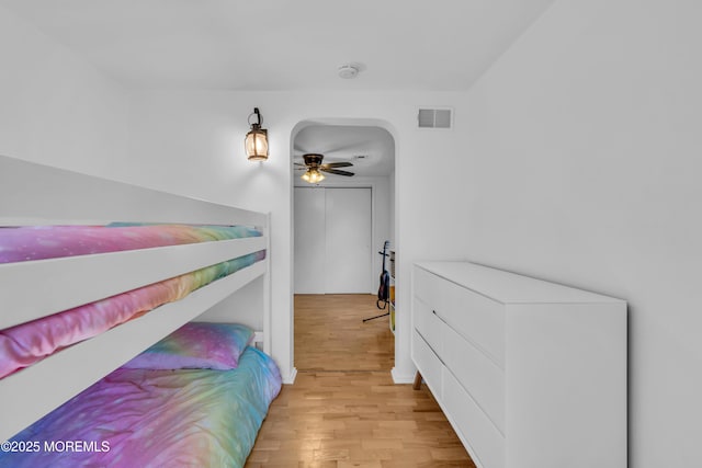 bedroom with light wood finished floors, baseboards, and arched walkways