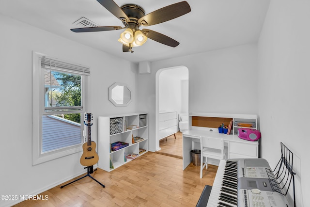 office with wood finished floors, a ceiling fan, and arched walkways