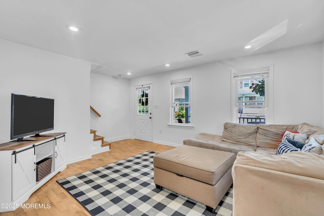living room featuring stairs, healthy amount of natural light, recessed lighting, light wood-type flooring, and baseboards