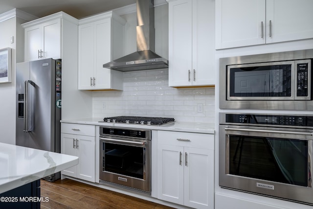 kitchen with appliances with stainless steel finishes, wall chimney range hood, white cabinetry, and dark wood-style floors