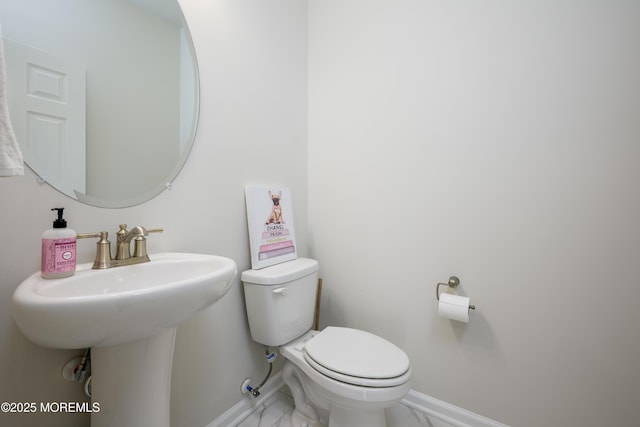 half bathroom featuring toilet, baseboards, and marble finish flooring