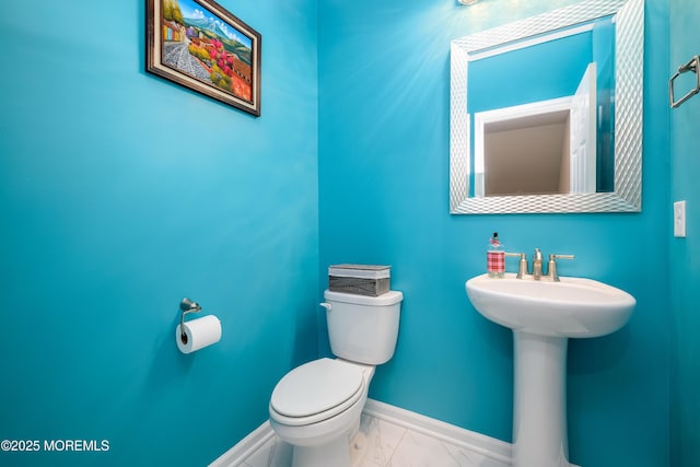 bathroom with marble finish floors, toilet, baseboards, and a sink