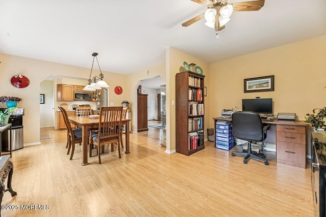home office featuring arched walkways, light wood-style floors, a ceiling fan, and baseboards
