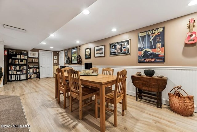 dining area featuring light wood finished floors, a wainscoted wall, and recessed lighting