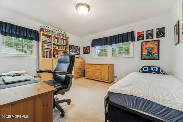 bedroom with light colored carpet and a desk