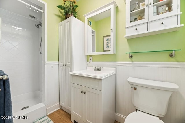 bathroom featuring toilet, a wainscoted wall, a stall shower, vanity, and wood finished floors