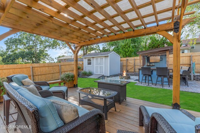 deck featuring an outdoor living space, a storage unit, an outbuilding, and a pergola