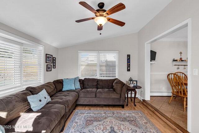 living room with a baseboard heating unit, plenty of natural light, vaulted ceiling, ceiling fan, and light wood-style flooring