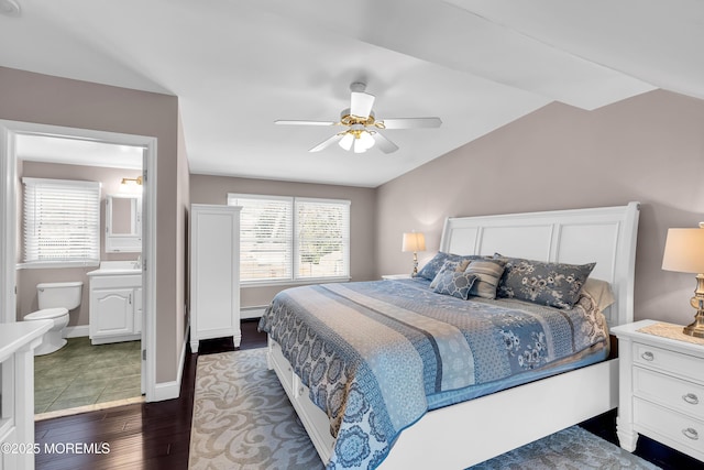 bedroom featuring vaulted ceiling, dark wood-style floors, baseboard heating, a ceiling fan, and ensuite bathroom
