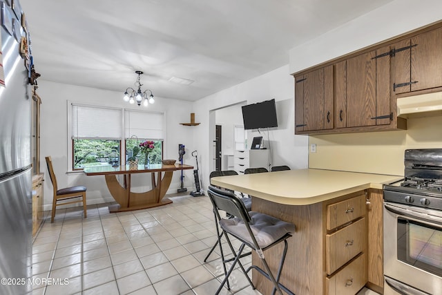 441 E Bird Village Rd, Jackson, NJ 08527 - kitchen featuring stainless steel appliances, under cabinet range hood, light tile patterned floors, a peninsula, and a chandelier