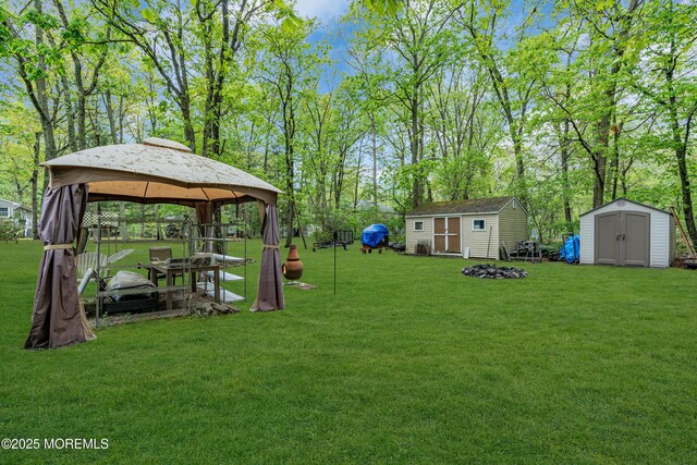 441 E Bird Village Rd, Jackson, NJ 08527 - view of grassy yard with a storage shed, a gazebo, an outbuilding, a fire pit, and view of wooded area