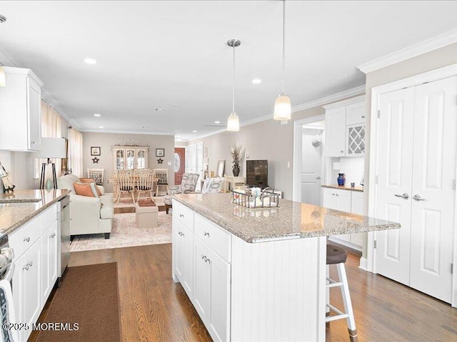 kitchen with crown molding, dark wood-type flooring, open floor plan, appliances with stainless steel finishes, and white cabinetry