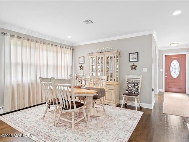 dining room featuring dark wood finished floors, ornamental molding, baseboards, and recessed lighting