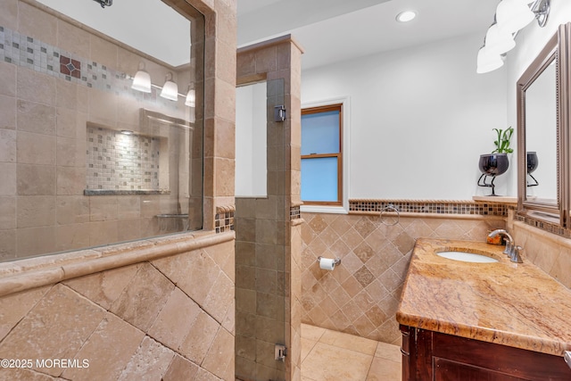 bathroom with tile walls, a tile shower, vanity, recessed lighting, and wainscoting