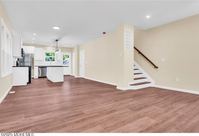 1031 3rd Ave, Asbury Park, NJ 07712 - unfurnished living room featuring light wood finished floors, recessed lighting, baseboards, and stairs
