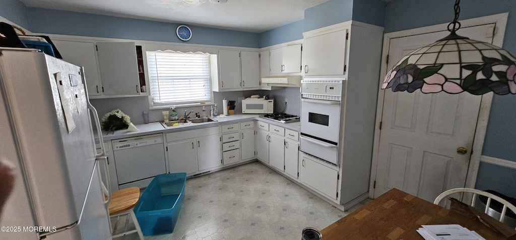 kitchen featuring white appliances, a warming drawer, under cabinet range hood, light floors, and a sink