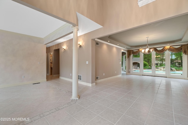 unfurnished living room featuring a raised ceiling, light tile patterned flooring, a chandelier, baseboards, and crown molding