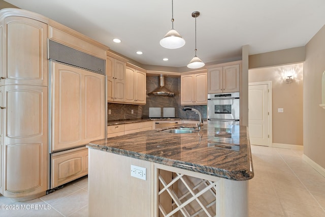 kitchen featuring paneled fridge, a sink, light brown cabinets, wall chimney exhaust hood, and light tile patterned floors