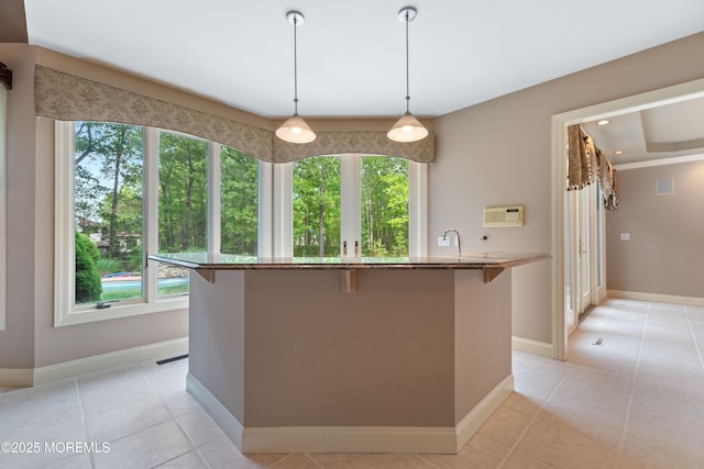 kitchen featuring a kitchen breakfast bar, baseboards, stone counters, light tile patterned floors, and recessed lighting