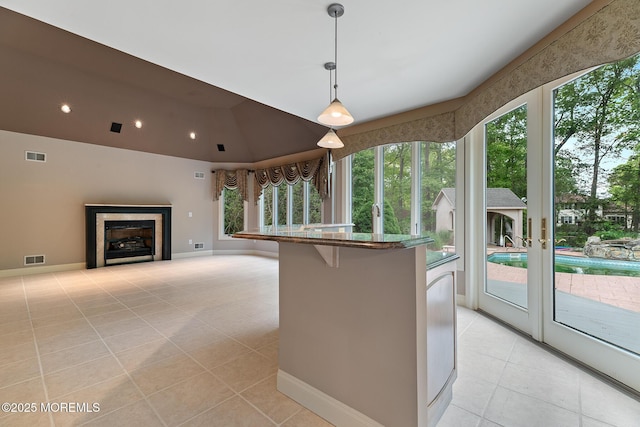 kitchen featuring light tile patterned flooring, stone countertops, a breakfast bar area, pendant lighting, and baseboards