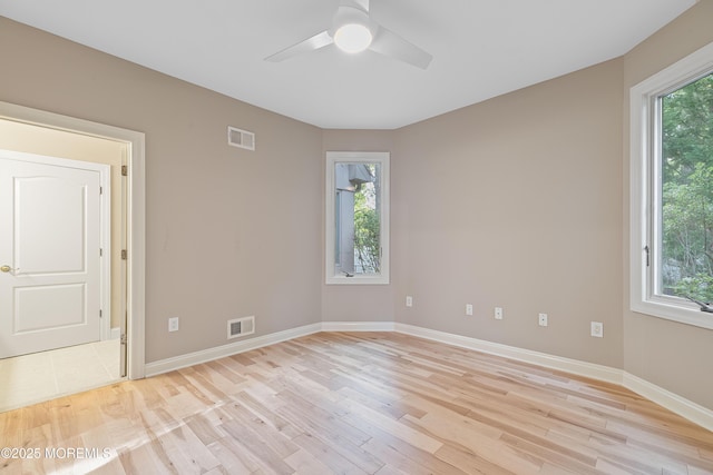 spare room featuring light wood-style flooring, a ceiling fan, and baseboards
