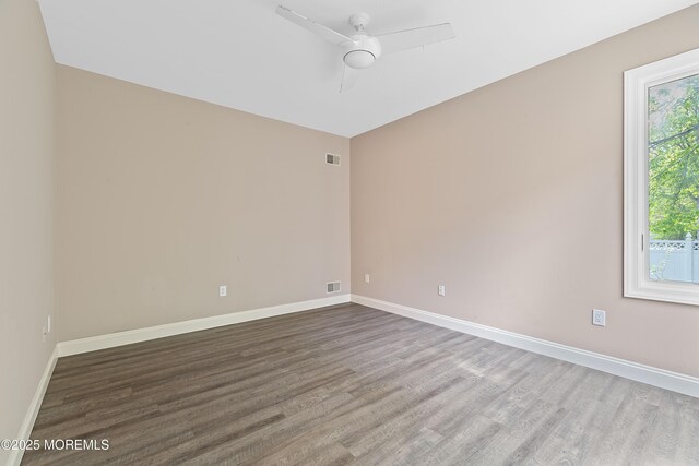 empty room with wood finished floors, ceiling fan, and baseboards