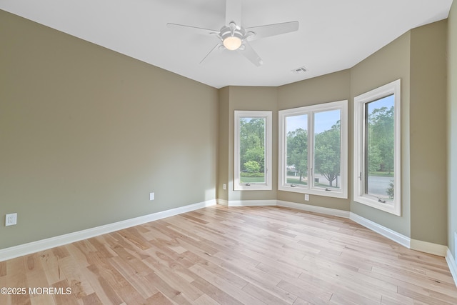 spare room with ceiling fan, light wood-type flooring, and baseboards