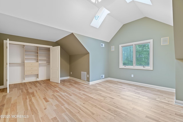 additional living space featuring a skylight, vaulted ceiling, light wood-style flooring, and baseboards
