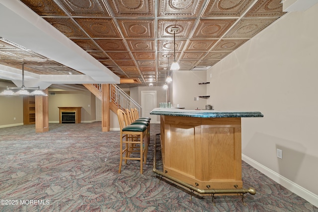 indoor wet bar featuring an ornate ceiling, carpet, baseboards, a fireplace, and stairs