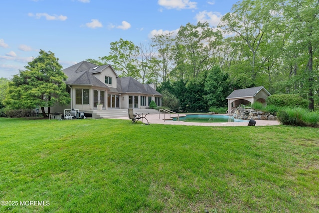 rear view of property featuring an outbuilding, a patio, a yard, and an outdoor pool