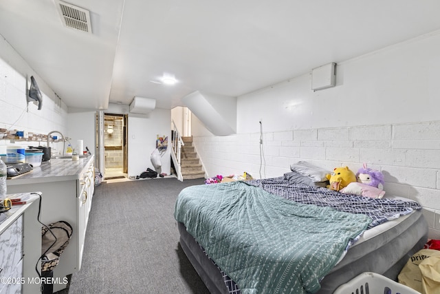 carpeted bedroom with a wall mounted air conditioner, a sink, and concrete block wall