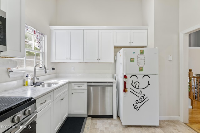 kitchen featuring appliances with stainless steel finishes, a sink, white cabinetry, light countertops, and a towering ceiling