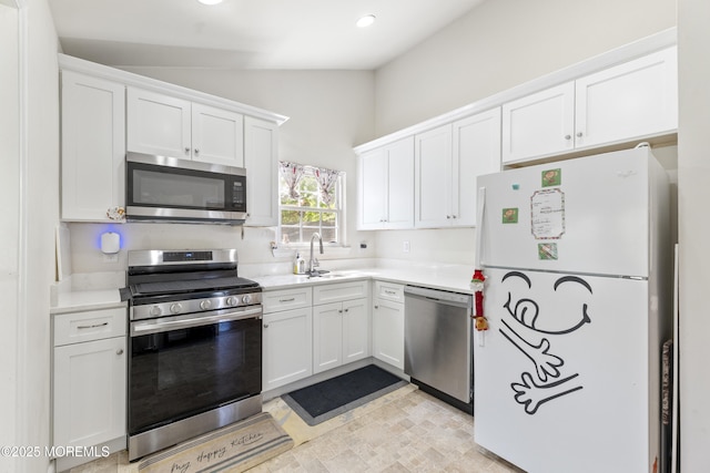 kitchen with stainless steel appliances, vaulted ceiling, a sink, white cabinetry, and light countertops