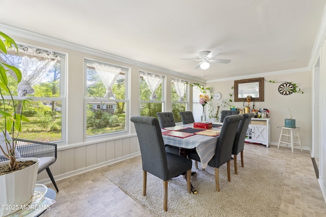 dining space with crown molding, a ceiling fan, stone finish floors, and baseboards