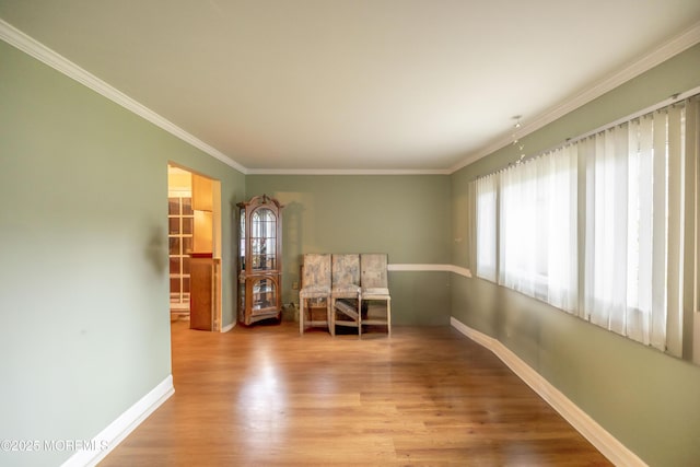 empty room featuring wood finished floors, ornamental molding, and baseboards