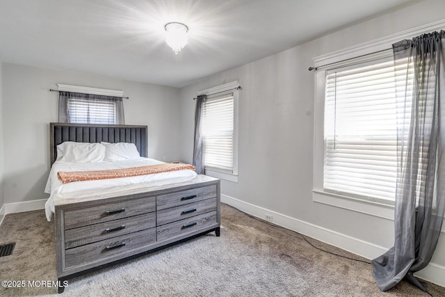 carpeted bedroom featuring multiple windows and baseboards
