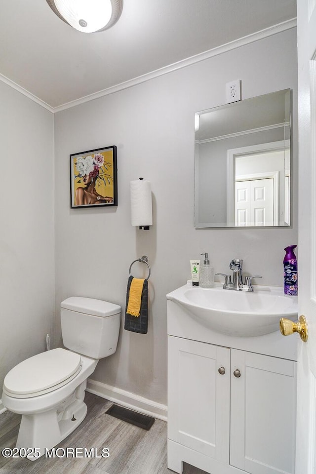 bathroom featuring wood finished floors, crown molding, toilet, baseboards, and vanity