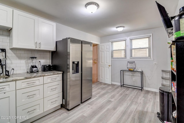 kitchen with stainless steel refrigerator with ice dispenser, tasteful backsplash, white cabinets, and light wood-style floors