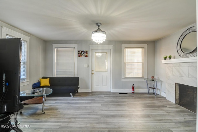 foyer featuring a tiled fireplace, wood finished floors, a chandelier, and baseboards