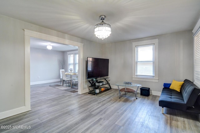 living area with wood finished floors, a chandelier, plenty of natural light, and baseboards