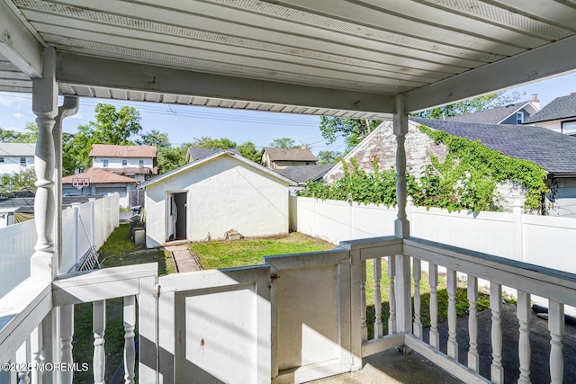 view of patio / terrace with a fenced backyard, an outbuilding, a storage unit, and a residential view