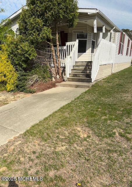 view of side of home featuring covered porch and a yard