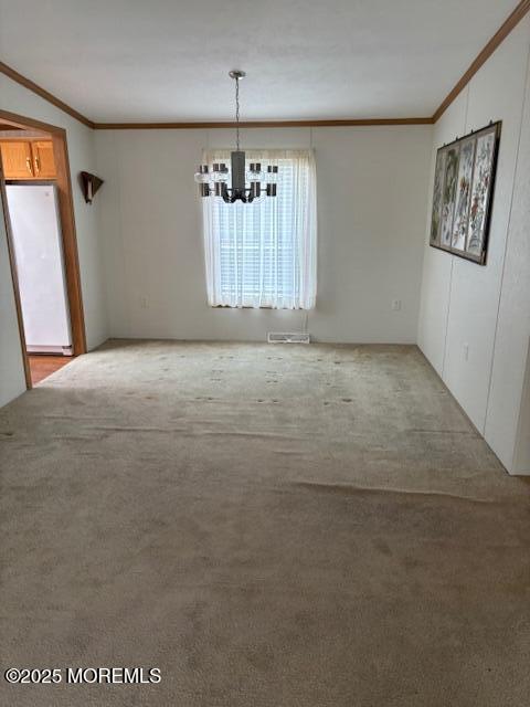 unfurnished dining area featuring ornamental molding, a chandelier, and light carpet