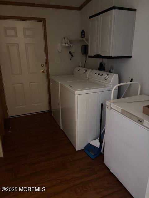 washroom with washing machine and clothes dryer, cabinet space, crown molding, and dark wood-style flooring