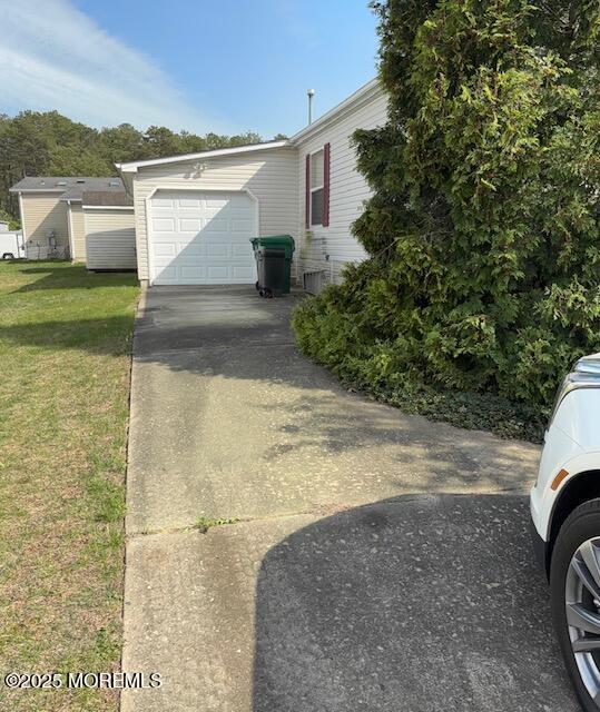 view of side of home featuring concrete driveway, a yard, and an attached garage
