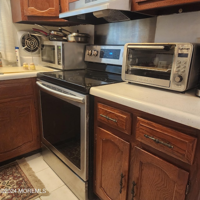 6 Conestoga Dr Unit C, Whiting, NJ 08759 - kitchen featuring appliances with stainless steel finishes, under cabinet range hood, light countertops, light tile patterned flooring, and brown cabinets