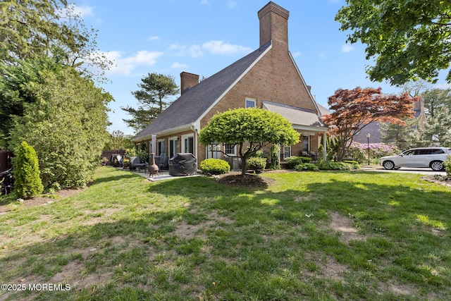 back of house with a chimney, a lawn, and brick siding