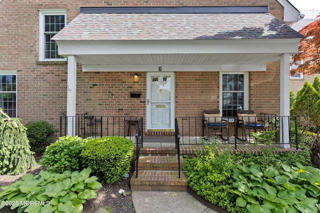 doorway to property featuring covered porch and brick siding